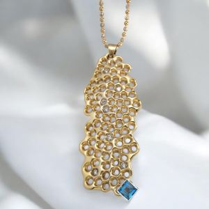 Handcrafted gold honeycomb necklace with a blue topaz gemstone and diamond accents, hanging on a silver chain.
