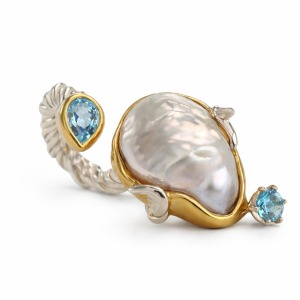 Baroque pearl ring with blue topaz accents in sculptural gold and silver design.